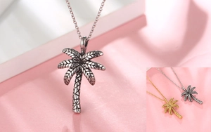 Detail showing palm tree necklace pendants in two-tone gold and vintage silver finishes