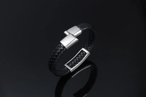 Detail of men's black braided leather bracelet with polished silver steel clasp