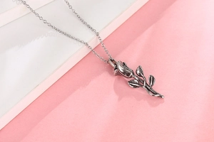 Détail du collier pendentif rose avec feuilles texturées et finition argentée oxydée