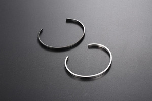 Detail of minimalist C-shape open bangles in brushed silver and matte black steel