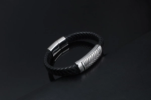 Macro shot of men's black braided leather bracelet with wheat pattern steel clasp