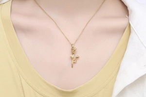 Gros plan d'un délicat collier avec pendentif rose porté au niveau de la clavicule