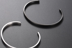 Detail of minimalist C-shape open bangles in brushed silver and matte black steel