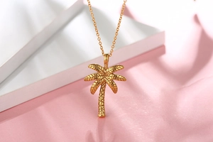Macro shot of gold palm tree necklace pendant with detailed tropical texture and fine chain
