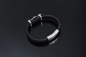 Detailed close-up of men's braided black leather bracelet with stainless steel clasp