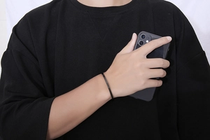 Close-up of a minimalist matte black C-shaped open cuff bracelet on a wrist