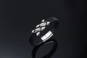 Detail of men's braided leather bracelet with magnetic clasp and textured steel elements