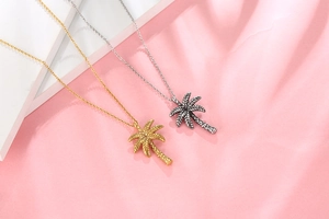Macro shot of palm tree pendants in gold and silver showing detailed leaf texture