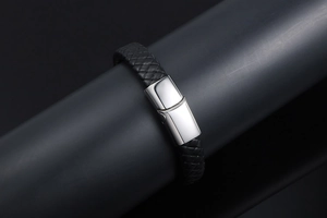 Detailed close-up of the woven black leather texture and polished steel clasp of the bracelet
