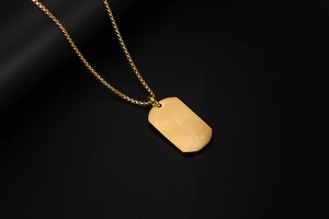 Vista detallada del collar con placa rectangular dorada con acabado cepillado y cadena elegante