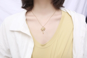 Detail of gold palm tree pendant necklace with fine textures worn on a model