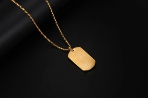 Vue détaillée du collier pendentif rectangulaire doré avec finition mate sur fond noir