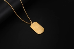 Detailed view of a golden minimalist dog tag necklace on a sleek black background