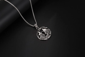 Détail d'un pendentif loup vintage et plumes en acier titane vieilli