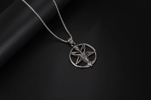 Macro shot of gothic Baphomet goat head pendant with box chain on dark background