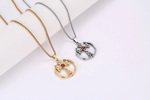 Dettaglio di collane con croce celtica oro e argento con pietra rossa su espositore