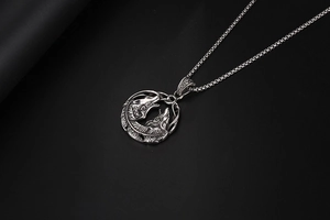 Vue macro d'un pendentif rétro en acier avec motif viking de deux loups et plumes