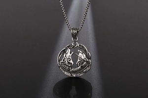 Détail macro du pendentif double loup et plume en acier rétro avec chaîne à billes carrée