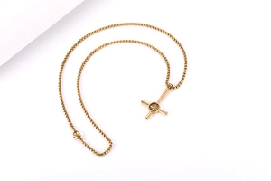 Dettaglio del ciondolo a croce dorata con motivo a stella su una collana a catena box