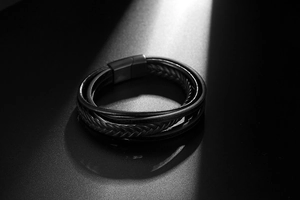 Close-up of men's multi-layer woven leather bracelet with matte black magnetic buckle
