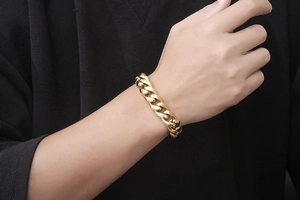 Gros plan d'un bracelet gourmette en titane doré porté sur un poignet masculin