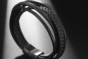 Close-up of men's multi-layer woven leather bracelet with matte black magnetic metal clasp