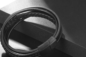 Macro detail of men's multi-layer woven leather bracelet with matte black magnetic clasp