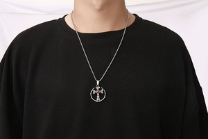 Dettaglio della collana a croce gotica con gemma rossa su uomo in felpa nera