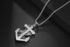 Detail of brushed titanium steel cross and anchor pendant with square link chain