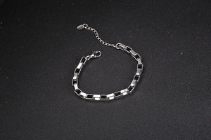 Detail view of silver rectangle link bracelet with lobster clasp on black background