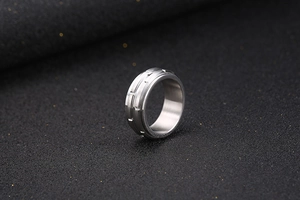 Close-up of titanium steel ring featuring industrial gear grooves on a black background