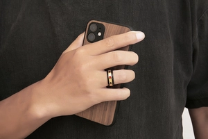 Gros plan d'une bague de poker or et noire avec motifs cœur et pique portee au doigt