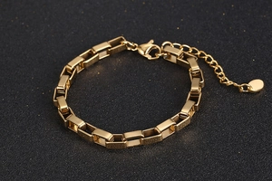 Close-up of golden box chain bracelet with lobster clasp and adjustable link on black background