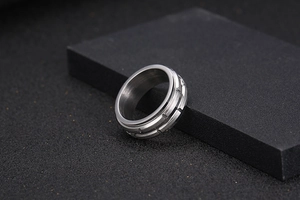 Macro shot of silver titanium rotating gear ring for men on black textured background
