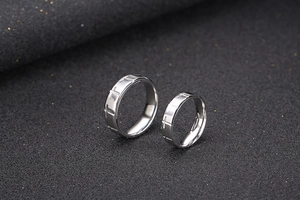 Close-up of titanium steel couple rings with embossed cross pattern on matte surface