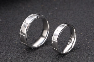 Macro shot of silver titanium steel couple rings with engraved cross patterns