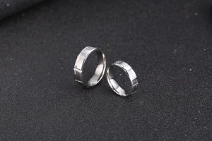 Detailed close-up of silver titanium steel couple rings with engraved cross patterns
