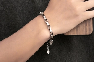 Adjustable titanium steel chain bracelet with rectangular links and metal tag on wrist