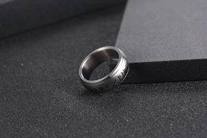 Macro shot of silver titanium steel ring with Nordic Rune symbols and brushed metal finish