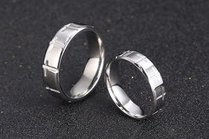 Detailed view of silver titanium steel couple rings with engraved cross patterns