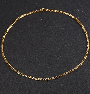 Detail of 18K gold-plated titanium steel Cuban chain with lobster clasp on black background