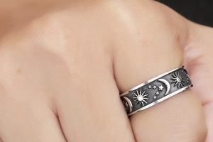 Macro shot of vintage stainless steel ring featuring embossed sun, moon and star patterns