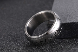 Macro detail of Nordic rune engravings on brushed titanium steel band for men