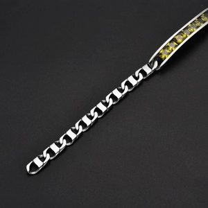 Gros plan d'un bracelet en acier titane avec des pierres carrées vert émeraude serties