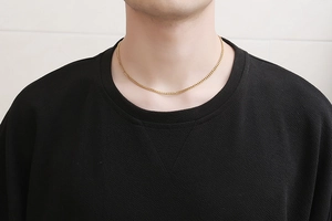 Detail of a men's gold-plated titanium steel necklace shown on a male model's neck
