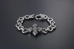 Macro detail of retro punk bracelet featuring engraved silver links and cross pendant