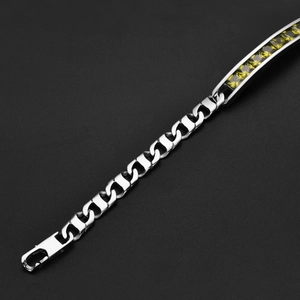 Détail macro du bracelet à chaîne gourmette argentée avec pierres jaune-vert carrées