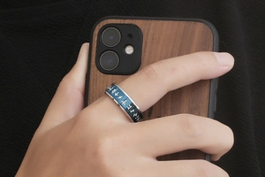 Detail of Viking style titanium steel ring with runes held against a wood grain phone