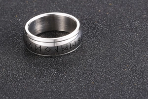 Macro shot of brushed titanium steel ring with black engraved Nordic rune symbols