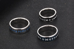 Detailed view of three titanium steel rings with Nordic runes in silver, black, and blue
